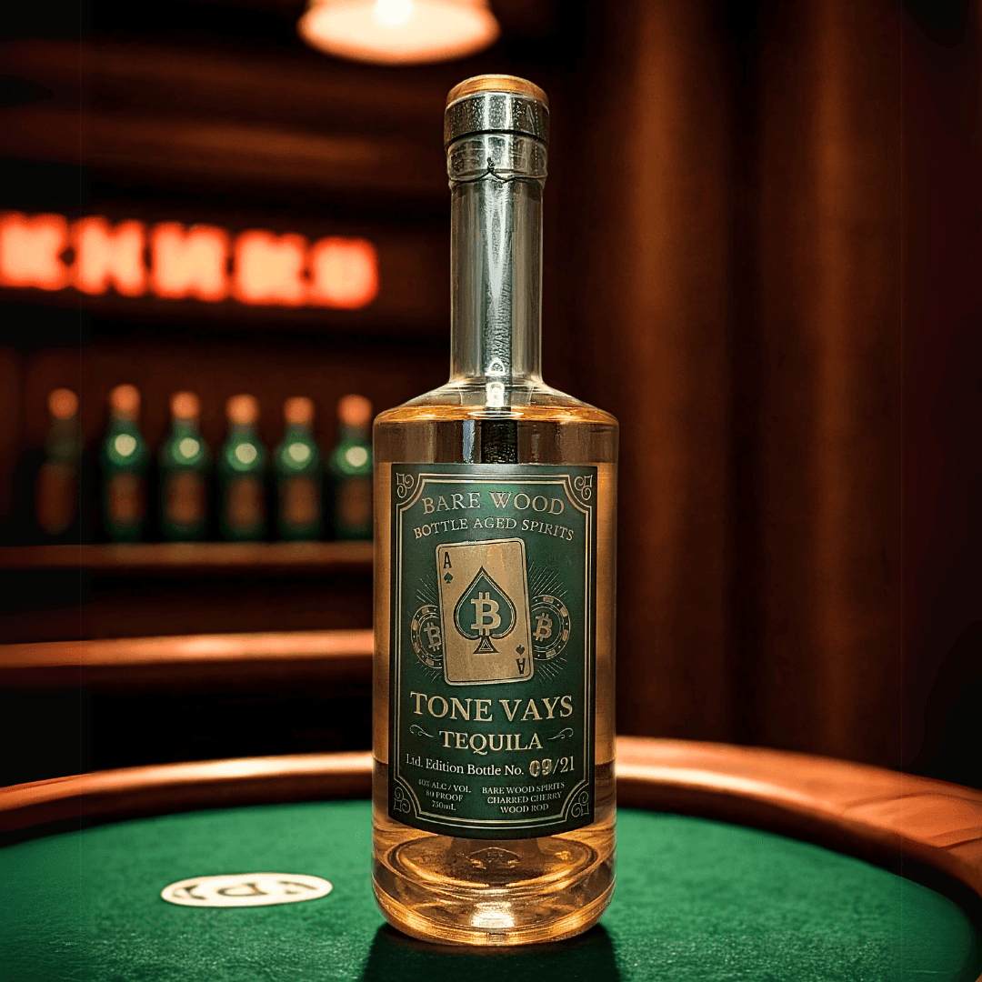 Bottle of Tone Vays tequila on a green table with blurred background display of bottles and lights.