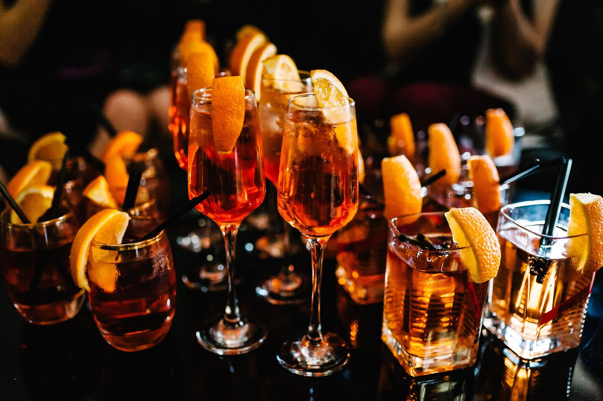 Closeup of gourmet old fashion martini drink in cocktail glass filled with bourbon, cognac and brandy garnished by delicately orange. grain, defocussed.